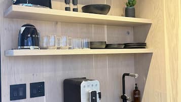 Une cuisine moderne équipée d’une cuisinière intégrée, d’une machine à café et d’une bouilloire posées sur le plan de travail.