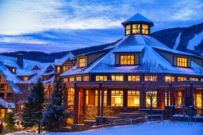 A large, multi-story building with a prominent tower and multiple windows, surrounded by snow-covered landscape.