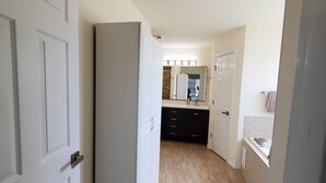 A hallway leading to a kitchen with a refrigerator, cabinets, and a tiled floor.