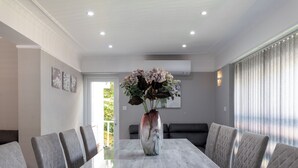 Ein Konferenzraum mit einem Marmortisch, grau gepolsterten Stühlen, einer Blumenvase und einem großen Fenster mit Vorhängen.