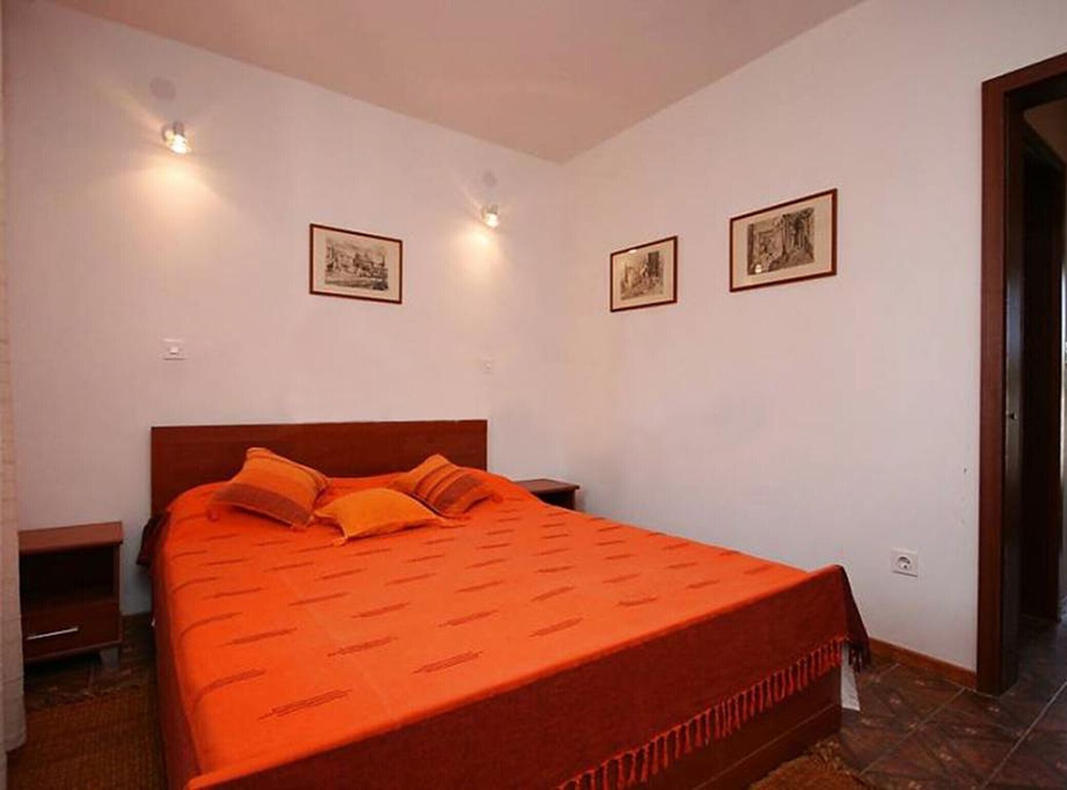 A bedroom with a single bed, two bedside tables, and two wall-mounted lights.