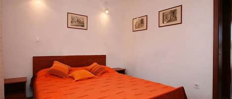 Un dormitorio con una cama individual, dos mesitas de noche y dos lámparas de pared.