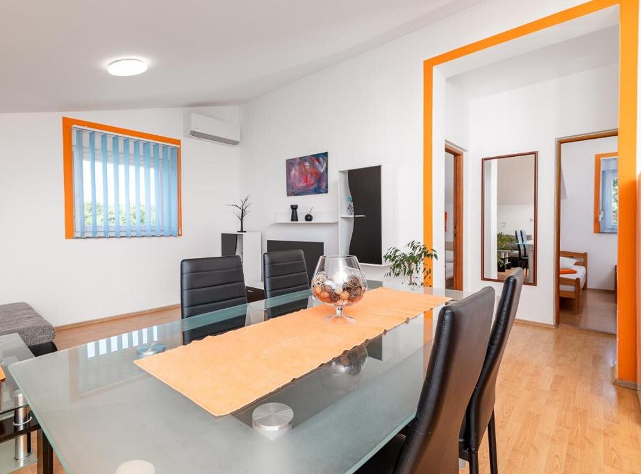 A modern meeting room with a glass table, black chairs, a fireplace, and a painting on the wall.