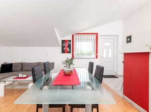 Ein modernes Wohnzimmer mit einem Glastisch, einer Couch und einer roten Akzentwand.