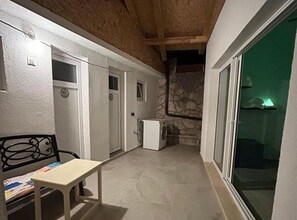 A narrow hallway with a bench, a washing machine, and a stone wall. - Three Bedroom Apartment with Sea View (Loviste)