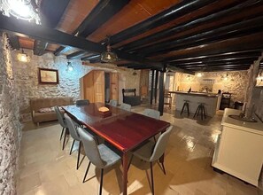 Ein rustikales Interieur mit einem Holzespeisetisch, Steinwänden und einer Küchenzeile.