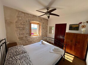 Ein Schlafzimmer mit Bett, Kleiderschrank, Fenster und Deckenventilator.