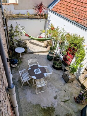A patio with a table and chairs, surrounded by potted plants and a hammock. - Artist's house · Terrace · Fécamp · Sleeps 4 (Fécamp)