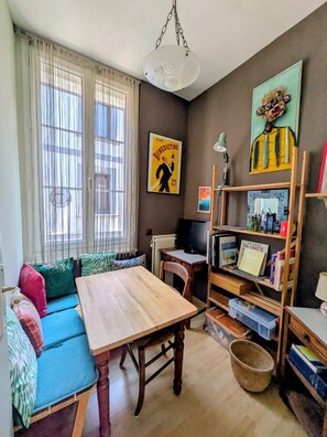 A cozy living room with a wooden table, a sofa with cushions, a television, and a bookshelf. - Artist's house · Terrace · Fécamp · Sleeps 4 (Fécamp)
