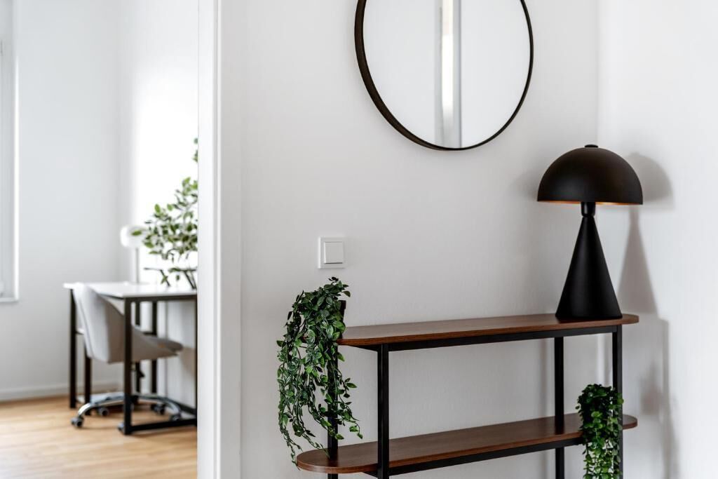 Ein modernes Zimmer mit Schreibtisch, Stuhl und einer Ablage mit Pflanze.