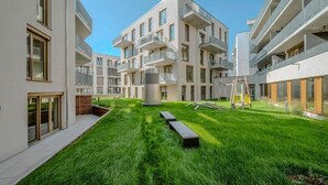 A modern apartment complex with multiple balconies, a central courtyard with grass, and a large cylindrical structure. - EXQUIS 3 Room Serviced Apartment (Böblingen)
