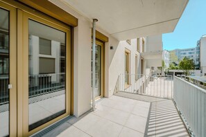 Um edifício moderno com grandes janelas de vidro, guarda-corpo metálico e piso revestido de azulejos.