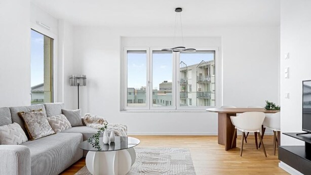 A modern living room with a sofa, a coffee table, and a dining area with chairs. - EXQUIS 3 Room Serviced Apartment (Böblingen)