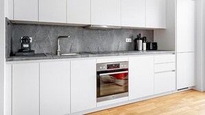 A modern kitchen with white cabinets, a built-in oven, and a marble countertop. - EXQUIS 3 Room Serviced Apartment (Böblingen)