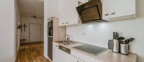 A modern kitchen with a dishwasher, oven, and stainless steel sink.