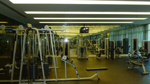 Un gimnasio con diferentes máquinas de ejercicio, una pantalla de televisión y un espejo.