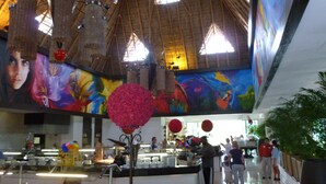 Um átrio amplo com teto alto, luminárias de vime decorativas e um mural na parede.