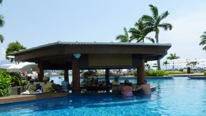 Zona de bar junto a la piscina, con piscina, palmeras y sillones reclinables.