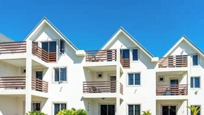 Un edificio residencial de varios pisos con balcones, ventanas y cielo despejado.