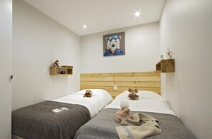 A bedroom with two beds, wooden headboards, and a painting of a bear on the wall. - 3rd floor, balcony, tv, ski locker, 38m², Les 2 Alpes (Mont-de-Lans)