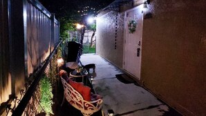 A narrow outdoor corridor with a chair and table, a small table with a plant, and a wall-mounted light fixture. - Cozy and comfy Apt. in the heart of Miami - 1-bedroom/1-bathroom with AC (Coral Gables)