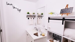 A bathroom with a white sink, a mirror, a towel rack, a shelf with plants, and a sign with bathroom rules. - Cozy and comfy Apt. in the heart of Miami - 1-bedroom/1-bathroom with AC (Coral Gables)
