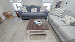 A living room with a grey sofa, a wooden coffee table, and a wicker basket. - Pelican Paradise, Piers, Pints, & Perfect Putts!  (Murrells Inlet)