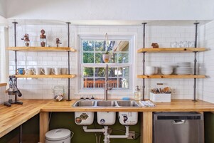 A kitchen with wooden shelves, a sink, and a dishwasher.