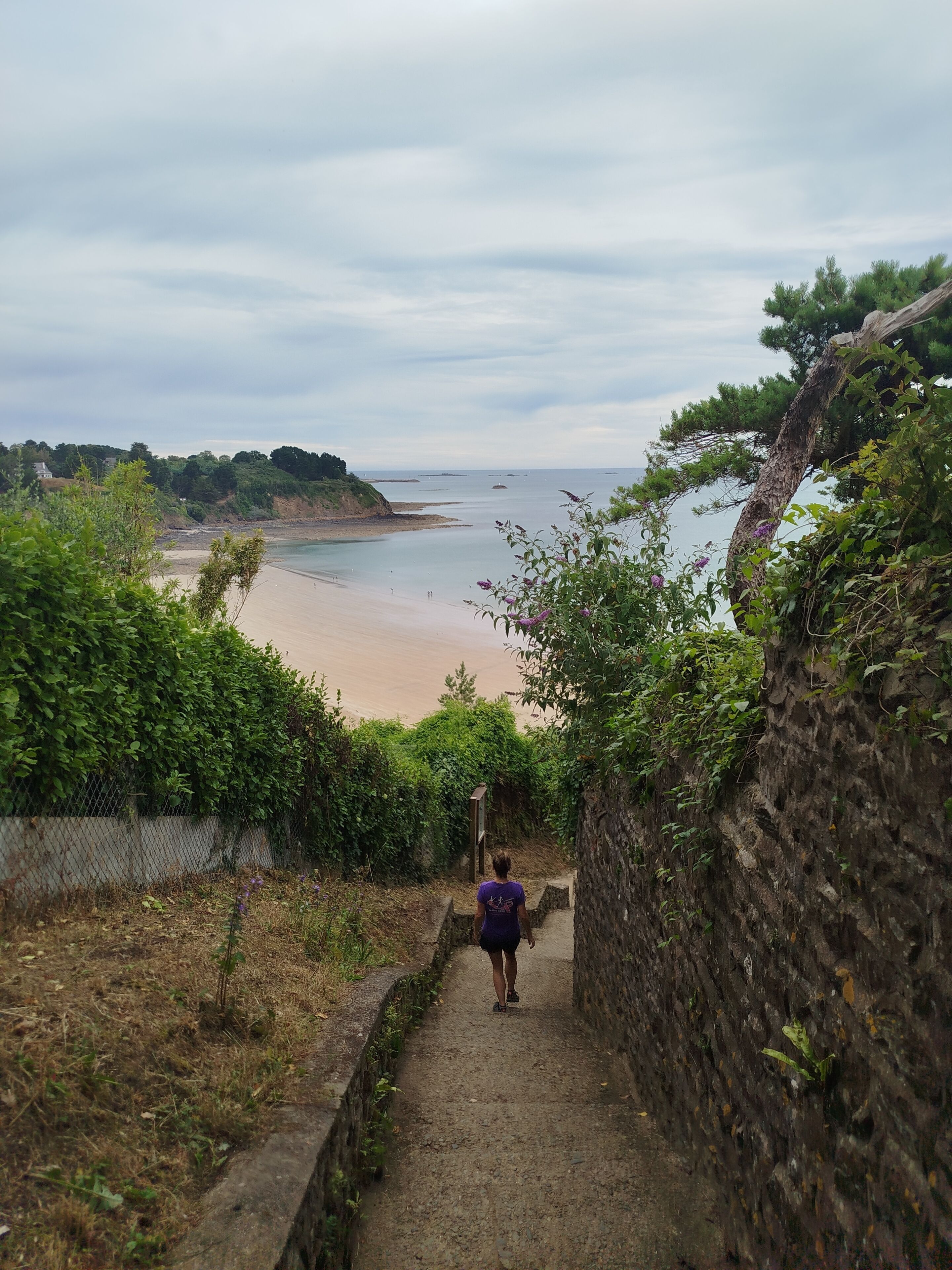 Un sendero que lleva a una playa con vista al mar y a tierra firme.