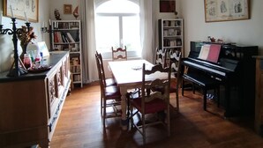 Una sala da pranzo con tavolo, sedie, un pianoforte e librerie.