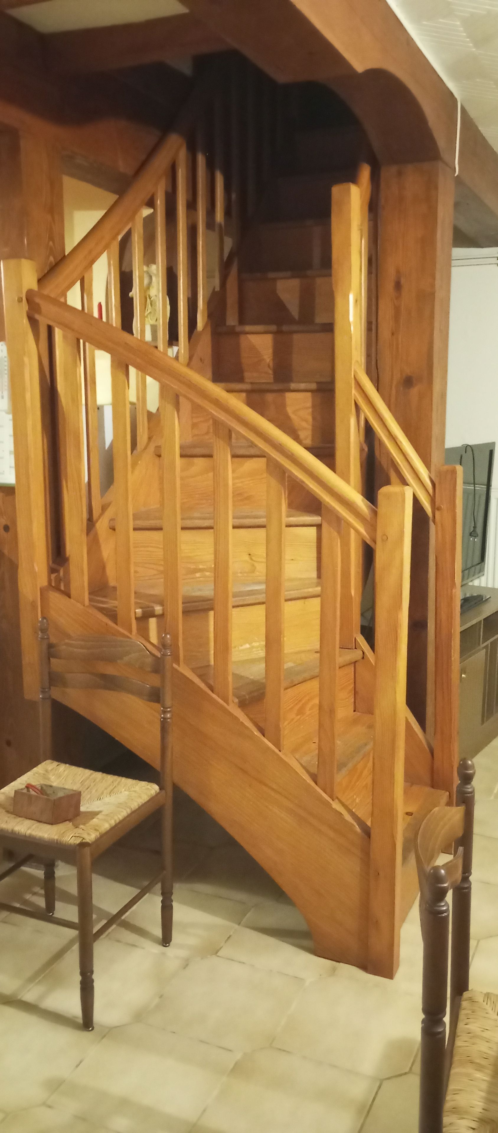 A wooden staircase with a handrail, a chair, and a small table.