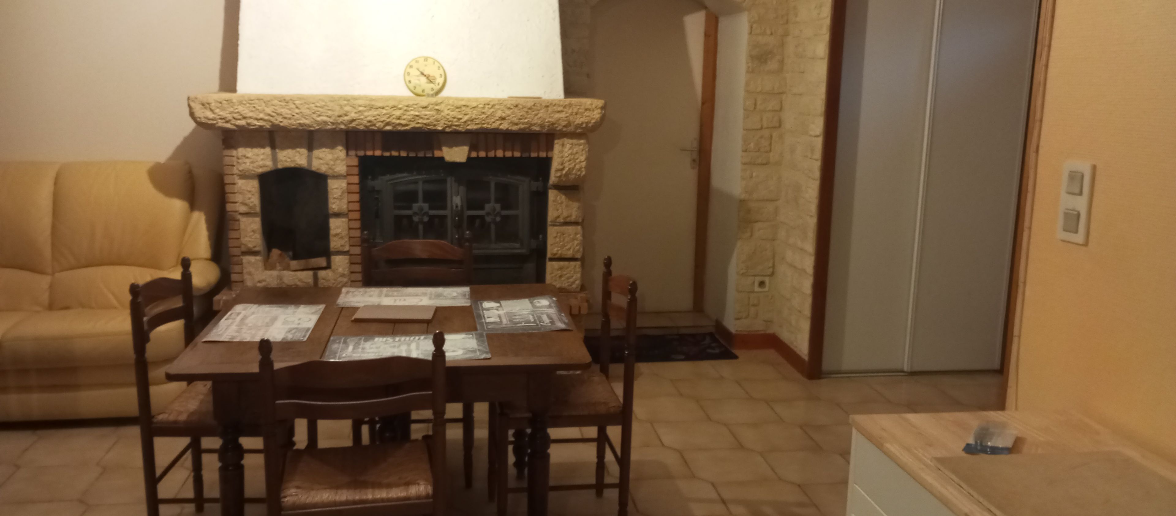 A living room with a fireplace, a dining table with chairs, and a sofa.