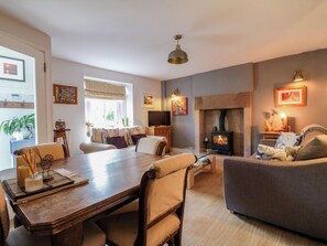 A cozy living room with a fireplace, a dining area with a wooden table, and a comfortable sofa. - Sunnyside (Matlock)