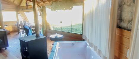 A wooden interior with a hot tub, a fireplace, and a view of the outdoors.