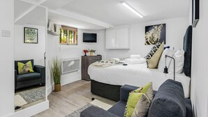 A modern bedroom with a bed, a sofa, a TV, and artwork on the walls. - Cosy Little Flat - Perfect Base for Explorers (London)
