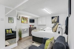 Ein modernes Schlafzimmer mit einem Bett, einer Couch, einem Fernseher und Kunstwerken an den Wänden.
