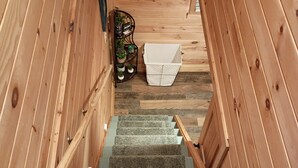 A wooden staircase with carpeted steps leading to a room with a ceiling light fixture.