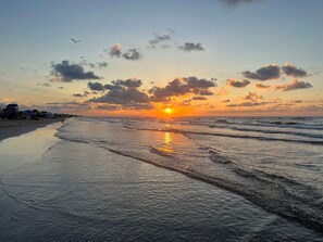 A beach with a sunset, waves, and a few birds. - Crystal Beach Serenity Escape: 4BR Beachfront! Stunning Views & Outdoor Showers (Bolivar Peninsula)