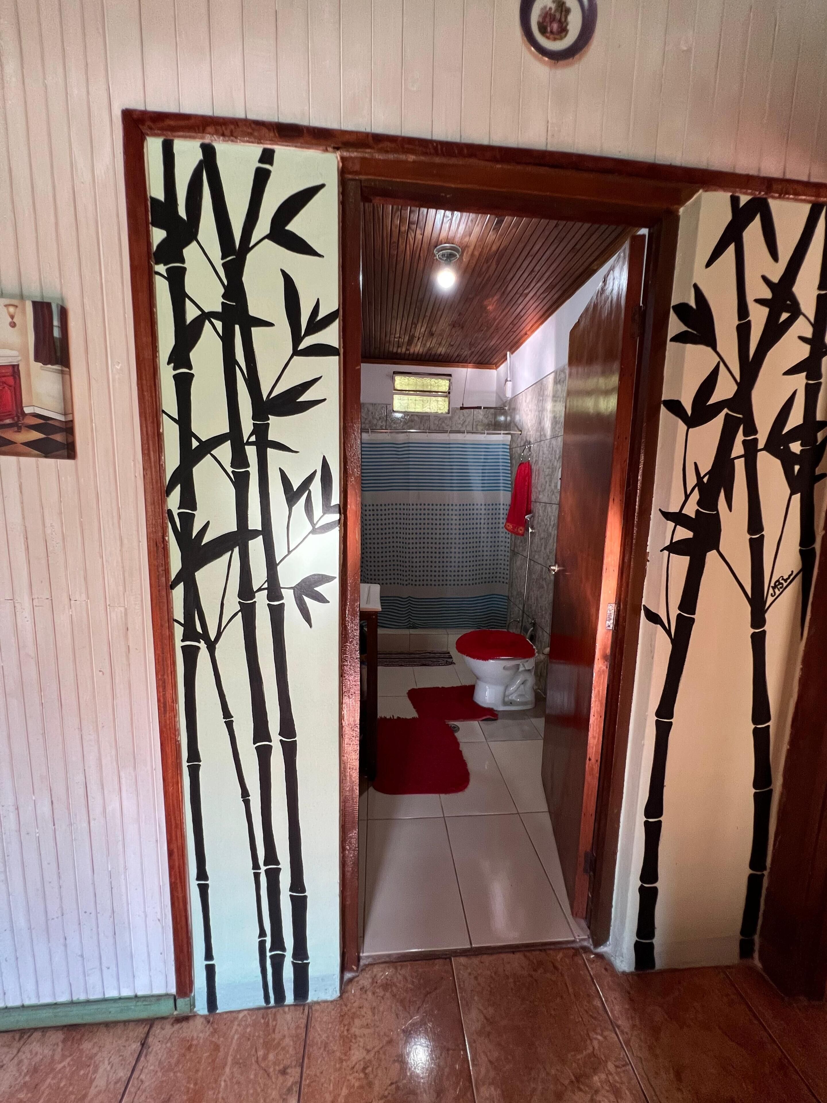 Un baño con inodoro, zona de ducha y un tapete rojo en el suelo.