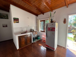 A compact kitchen with wooden cabinets, a white refrigerator, and a window providing natural light.