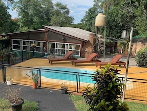 A pool area with lounge chairs, a building with large windows, and a water tank.