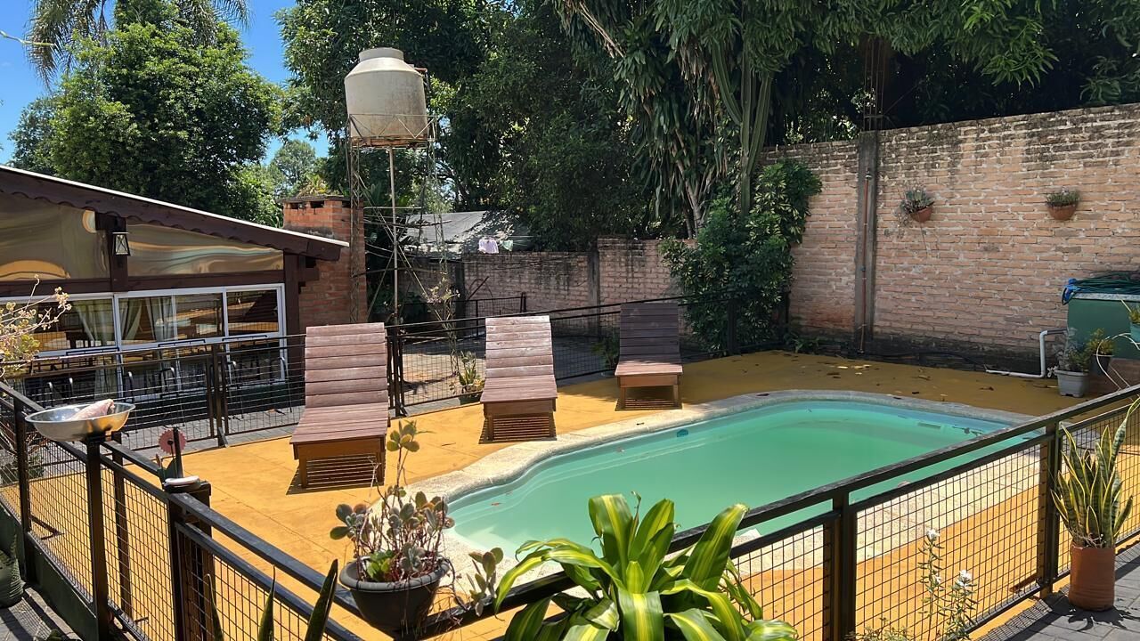 Patio con piscina, terraza de madera y mobiliario exterior.