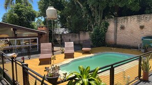A backyard with a swimming pool, wooden deck, and outdoor seating.