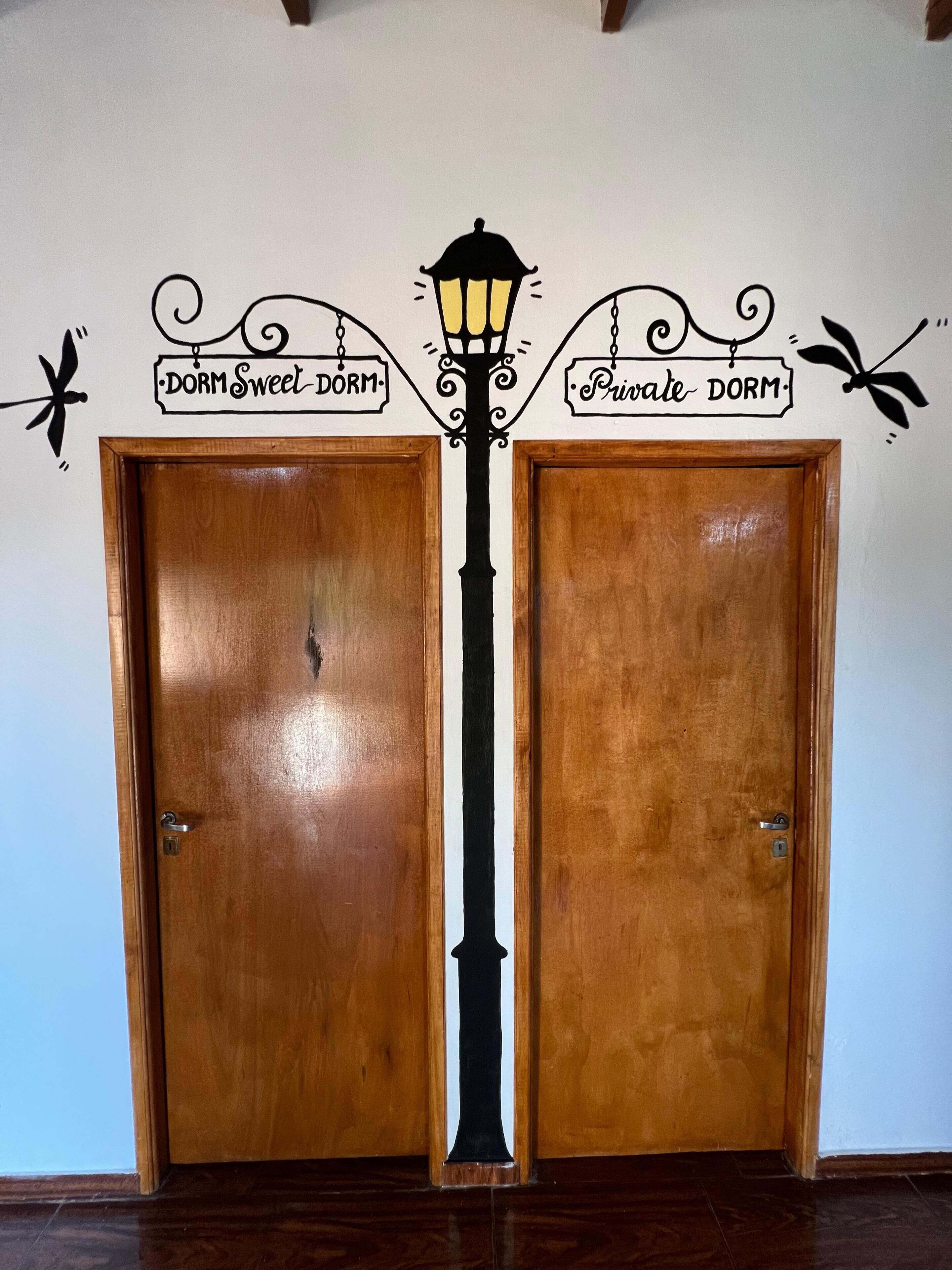 Duas portas de madeira com um aplique na parede e adesivos decorativos entre elas.