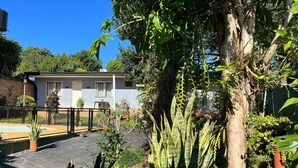 A residential area with a house, a fenced yard, and various potted plants. - Lost & Found Iguazú Hostel (Puerto Iguazu)