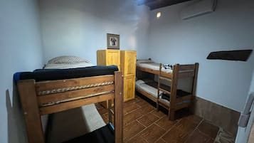 Una habitación pequeña y funcional con literas, un armario de madera y un cuadro en la pared.