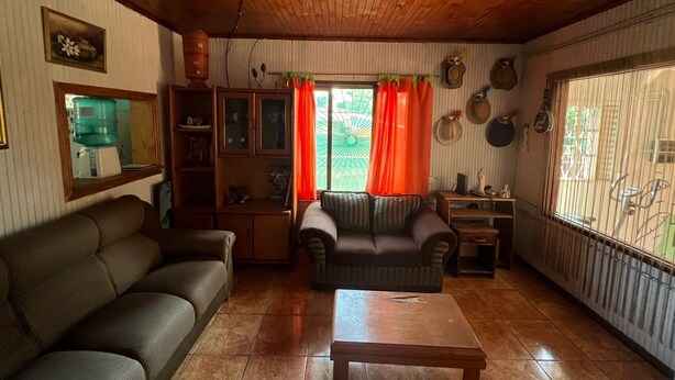 A living room with a sofa, a coffee table, and a window with curtains. - Lost & Found Iguazú Hostel (Puerto Iguazu)