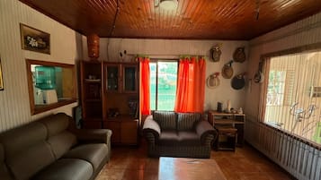 Una sala de estar con sofá, mesa de centro y ventana con cortinas.