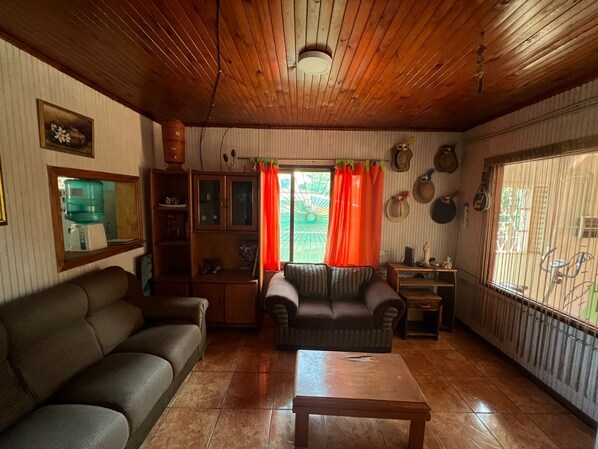 A living room with a sofa, a coffee table, and a window with curtains.