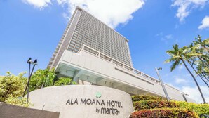 En hög hotellbyggnad med modern design, med en framträdande entré och en skylt med texten ”ALA MOANA HOTEL by mantra”.